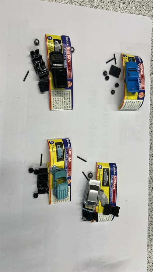 Kinder-Überraschungseier mit vier verschiedenen Autos zum Zusammenbauen; verschiedene Farben und Modelle.